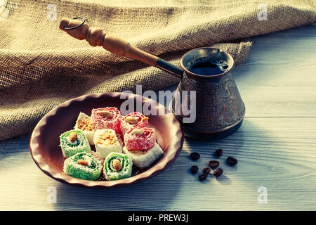 Turkish Delight auf Lehm Platte mit Kupfer cezve mit Kaffeebohnen auf Holzbrett mit Sack Stockfoto