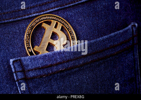Gold bitcoin in der gesässtasche der Jeans, Hintergrundbild Stockfoto