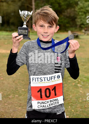 10 Jahre alter Junge stolz seine Medaille und Pokal Anzeige nach dem Gewinn einer 2,5 km querfeldein laufen Rennen, Hindhead, Surrey, Großbritannien. Sundy, 30. September 2018. Stockfoto