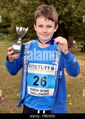 Acht Jahre alten Jungen stolz seine Medaille und Pokal Anzeige nach dem Gewinn einer 1 km querfeldein laufen Rennen, Hindhead, Surrey, Großbritannien. Sonntag, 30 September 2018. Stockfoto