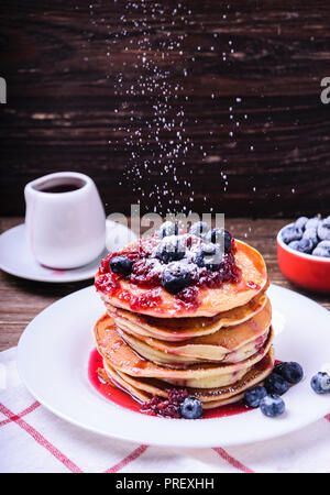 Stapel von amerikanischen Pfannkuchen mit himbeermarmelade und Heidelbeeren. Leckeres Frühstück. Gießen Puderzucker. Stockfoto