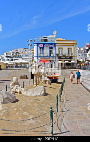 Eine Gruppe von Statuen der Darstellung eines Fischers Familie, die auf der Promenade neben Praia Peneco, summerAlbufeira, Algarve, Portugal Stockfoto