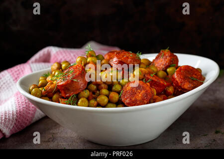 Eintopf aus Erbsen, Karotten und Würstchen in einer weißen Schüssel Stockfoto