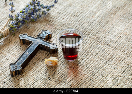 Die Gemeinschaft mit einem Glas Wein und Brot in der Nähe von Cross und lavanda auf dem Textil Tischdecke. Stockfoto