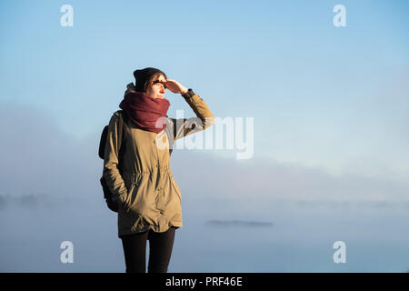 Frau steht in der Morgensonne vor der schönen Natur Landschaft im Nebel bedeckt. Weibliche Wanderer genießen Rising Sun in Misty natürlichen Hintergrund Stockfoto