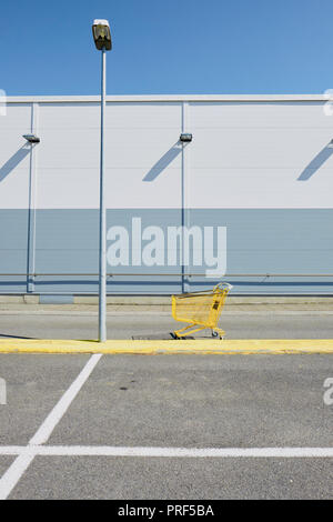 Ein einsamer Single gelb Warenkorb/Trolley in einem leeren Supermarktparkplatz Einstellung. Stockfoto