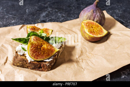 Feigen Früchte Sandwich auf ein Papier auf einen schwarzen Stein Hintergrund Stockfoto