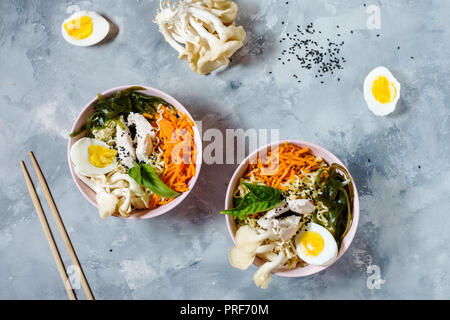 Miso Ramen asiatische Nudeln in Schalen auf konkreten Hintergrund. Ansicht von oben Stockfoto