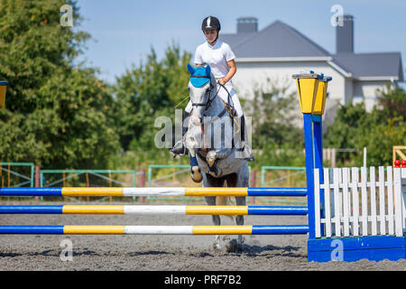 Pferdesport. Junge Mädchen springen über Hindernis auf Reitturnier Stockfoto