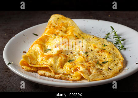 Rührei oder Omelett aus Eiern und Käse mit Kräutern auf der Platte gemacht Stockfoto