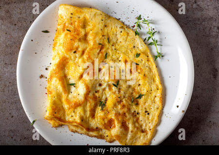 Rührei oder Omelett aus Eiern und Käse mit Kräutern auf der Platte - Ansicht von oben Stockfoto