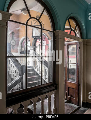 Blick durch hölzerne Tür und Zeichenreihen dahingehend überprüft, Treppe mit Laterne Stockfoto