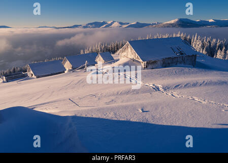 Winterlandschaft. Holzhäuser im Schnee. Bergdorf der Hirten. Sonniges Wetter in den Morgen. Karpaten, Ukraine, Europa Stockfoto