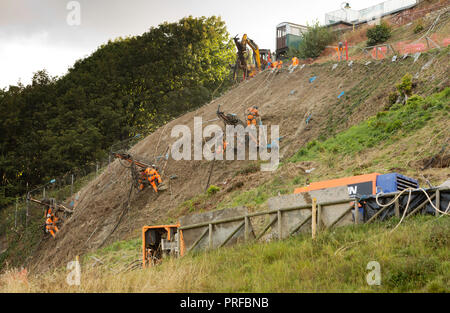 Bauingenieure in Kabelbäumen durch lange Kabel arbeiten an eine Felswand in Scarborough Stockfoto