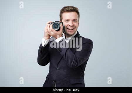 Say Cheese Konzept. Hübscher junger Mann in Anzug Holding in die Arme kleine Kamera bereit, ein shooting zu machen. Stockfoto