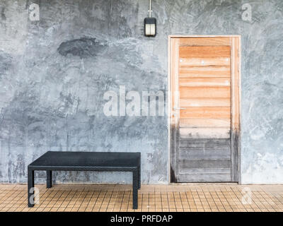 Hölzerne Tür auf dem Dachboden style Wand und schwarze rattan Sitzbank der modernen Haus. Stockfoto