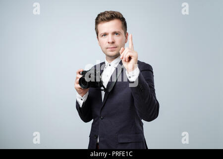 Say Cheese Konzept. Hübscher junger Mann in Anzug Holding in die Arme kleine Kamera bereit, ein shooting zu machen. Stockfoto