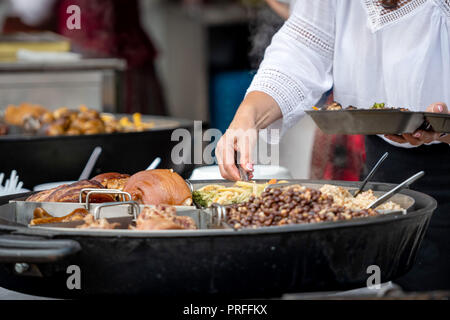 Lettische Nationale Küche. Eine Frau bringt warme Speisen aus einer großen Pfanne. Stockfoto