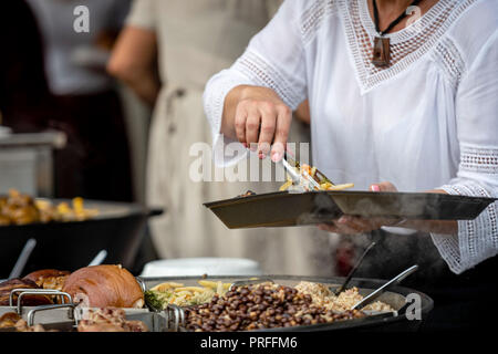 Lettische Nationale Küche. Eine Frau bringt warme Speisen aus einer großen Pfanne. Stockfoto