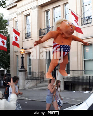 London, GB, 13. Juli 2018. 100.000 Menschen protestieren gegen den Besuch des US-Präsidenten Donald Trump. Die Demonstranten versammeln sich auf dem Trafalgar Square. Zwei junge Frauen tragen einen großen Bildnis von Donald Trump. Stockfoto