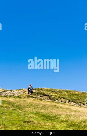 Zwei Menschen, ein erwachsenes Paar, Mann und Frau, auf dem Wanderweg Richtung Süden vom Gipfel des Cat Glocken (451 Meter) in der Nähe von Keswick, Cumbria. Stockfoto