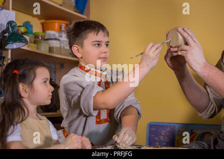 Keramik Klasse und Workshop: Professionelle männlichen Potter, die mit Kindern arbeiten und zeigen, wie keramische Waren in der Keramik Studio zu machen. Handgefertigte, educatio Stockfoto