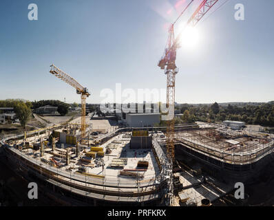 Eine Baustelle von einem modernen Gebäude mit zwei Kränen im Sonnenlicht. Stockfoto