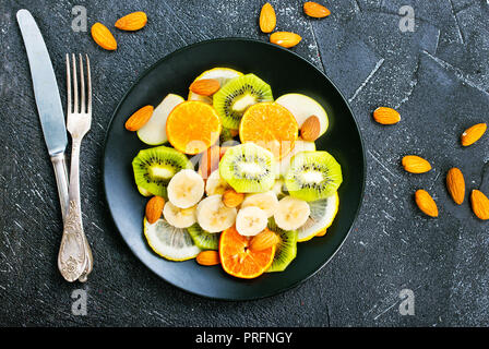 Obstsalat mit Mandeln auf schwarze Platte Stockfoto