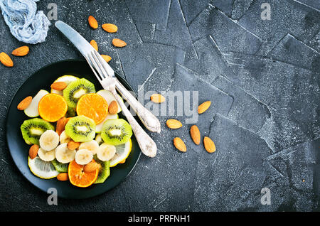 Obstsalat mit Mandeln auf schwarze Platte Stockfoto