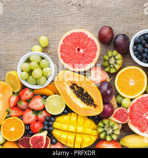 Bunte Früchte, Erdbeeren, Blaubeeren, Mango, Orange, Grapefruit, Bananen, Papaya apple, Trauben, Kiwis auf dem Holz Hintergrund, kopieren Platz für Text Stockfoto