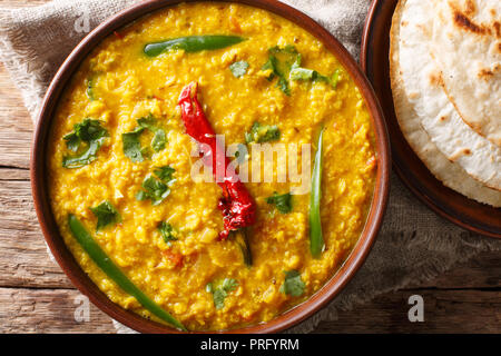 Linsensuppe Dal Tadka in eine keramische Schüssel mit Naan Brot auf einem hölzernen Hintergrund. Schließen oben. horizontal oben Ansicht von oben Stockfoto