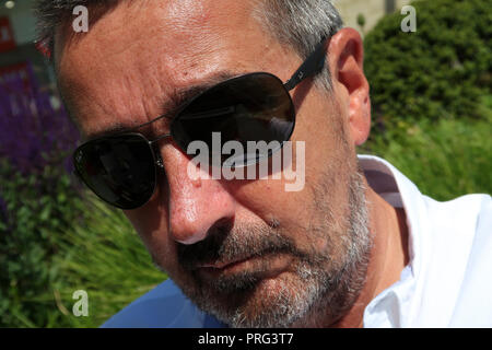 Portrait von im mittleren Alter, der Mann mit der Sonnenbrille und der Arbeitsscheinwerfer zur Kontrolle der Schnitthöhe Stockfoto