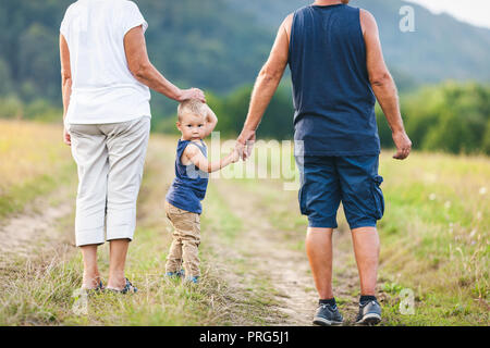 Glückliche Großeltern auf einem Spaziergang ausserhalb mit ihren Enkel Stockfoto