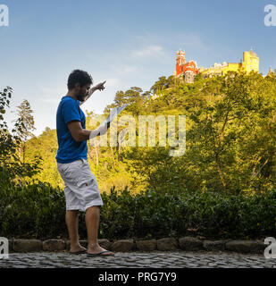 Junger Mann (20-25) touristische Holding eine Karte und gleichzeitig auf das Pena National Palast, ein Romantiker Palace in São Pedro de Penaferrim, Sintra, Stockfoto