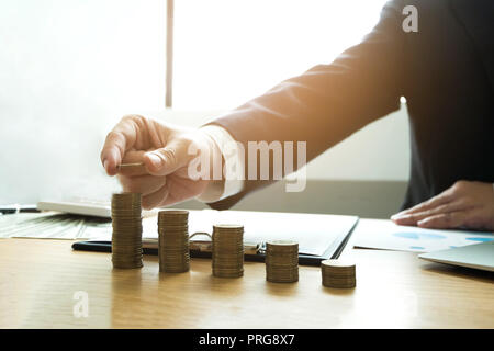 Geschäftsmann nimmt Münzen auf den Tisch und zählt Geld. Geschäftskonzept. Stockfoto