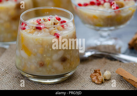 Traditionelle türkische Desserts Asure oder Ashure aus gekochtem Getreide mit getrockneten Früchten und Granatapfel Körner. Sie ist bereit, in die Glasschale auf zu dienen Stockfoto