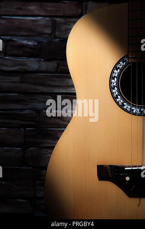 Ein Lichtstrahl fällt auf einer akustischen Gitarre steht auf einer Mauer. Stockfoto