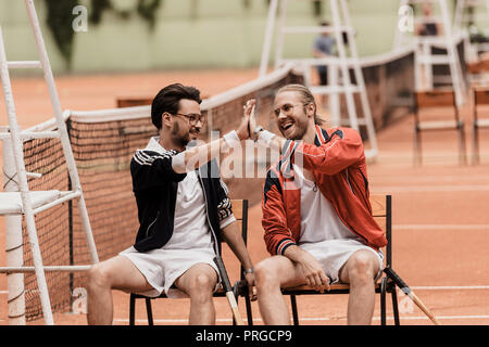 Lächelnd im Retrostil tennis Spieler hoch fünf am Tennisplatz Stockfoto