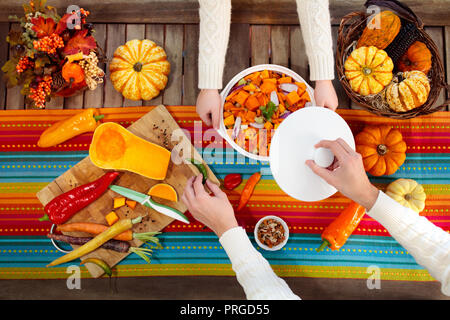 Mutter und Tochter schneiden Kürbis, Zwiebel und Karotte, kochen Suppe für Herbst Mahlzeit. Gesunde Herbst Gemüse für Halloween saison Mittagessen. Squash Schnitt auf Stockfoto