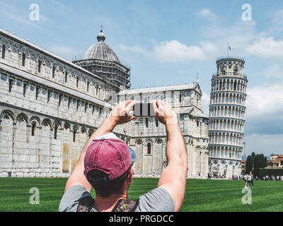 Stilvolle Kerl mit einem Telefon, die Bilder von der Schiefe Turm von Pisa an einem sonnigen, klaren Tag. Begriff der Freizeit, Reise und Tourismus Stockfoto