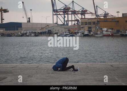 Malaga, Spanien. 2. Okt, 2018. Ein Migrant auf dem Boden betet gesehen, nachdem sie durch das Spanische Rote Kreuz unterstützt wird bei seiner Ankunft, ein beiboot am Hafen von Malaga. Spaniens Maritime Rescue Service gerettet 63 Migranten an Bord jollen am Mittelmeer und brachte sie nach Malaga Hafen, wo sie durch das Spanische Rote Kreuz unterstützt wurden. Credit: Jesus Merida/SOPA Images/ZUMA Draht/Alamy leben Nachrichten Stockfoto