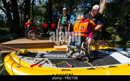 Lueneberg, Niedersachsen. 27 Sep, 2018. Sascha Roth-Pretzel (r) drückt Margret Homola und ihrem Rollstuhl auf einen speziellen Stand-up paddling Board. Danach gehen Sie mit dem Vorstand über die Ilmenau. (Dpa' Fliegen, Tauchen, Skaten, Paddeln: rollis neue Grenzen' vom 03.10. 2018) Credit: Philipp Schulze/dpa/Alamy leben Nachrichten Stockfoto