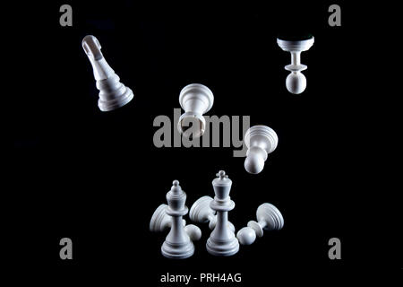 Fliegende weiße Schachfiguren auf schwarzen Hintergrund isoliert, Königin und König Stehend vorne. Stockfoto