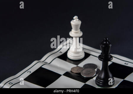 Zwei schach Könige vor jedem anderen ständigen, Münzen zwischen ihnen. Strategie, Finanzen, Business Konzept. Stockfoto