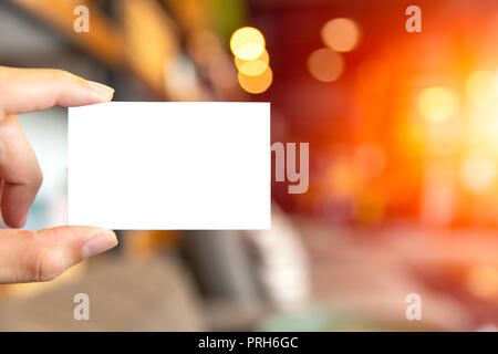 Hand, die leere weiße Visitenkarte mit blur cafe Hintergrund Stockfoto