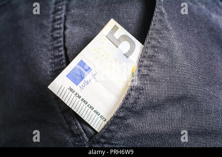 Die Hälfte der einen 5 Euro Schein zeigen aus der Tasche eine schwarze Jeans Hose - Armer Mann Konzept Stockfoto
