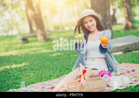 Cute teen geben Obst zum Essen gesund essen beim Picknick im Park Konzept. Stockfoto