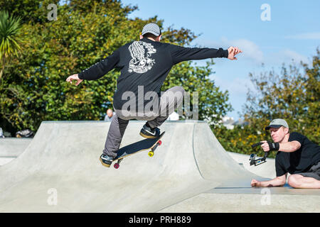 Ein Skateboarder gefilmt wird eine Antenne Trick an konkreten Wellen Skateboarding Park in Newquay in Cornwall. Stockfoto