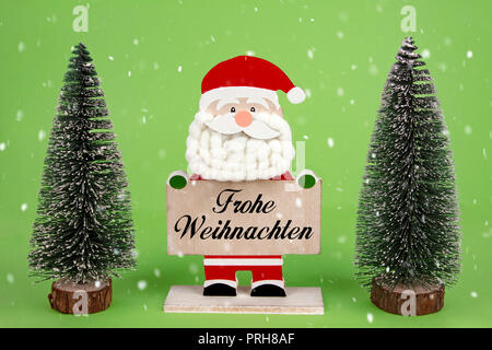 Dekorative Holz- Santa Clause Holding ein Board mit deutschem Text - Frohe Weihnachten - Merry Christmas Stockfoto