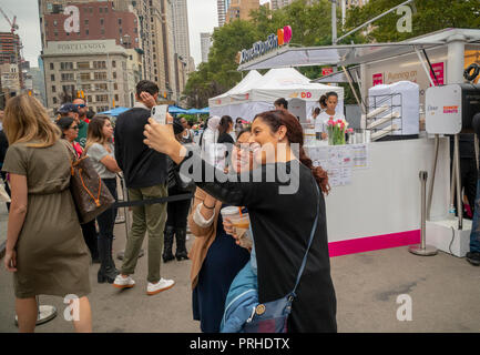 Millennials posieren für ein selfie an den Dunkin' und Taube Zusammenarbeit Branding event in Flatiron Plaza in New York am Montag, 1. Oktober 2018. Die Besucher waren von dem kostenfreien Tassen Kaffee und Proben der von Unilever, Dove Marke trocken Shampoo behandelt. Offenbar, so die Veranstalter Frauen auf Dunkin' und trocken Shampoo ermöglicht Ihnen so schnell aufstehen und morgens laufen. Dunkin' Brands vor kurzem änderte ihren Namen ablegen moniker 'donuts' besser Rechnung zu tragen, dass 60 Prozent der Verkäufe sind Kaffee Getränke. (Â© Richard B. Levine) Stockfoto